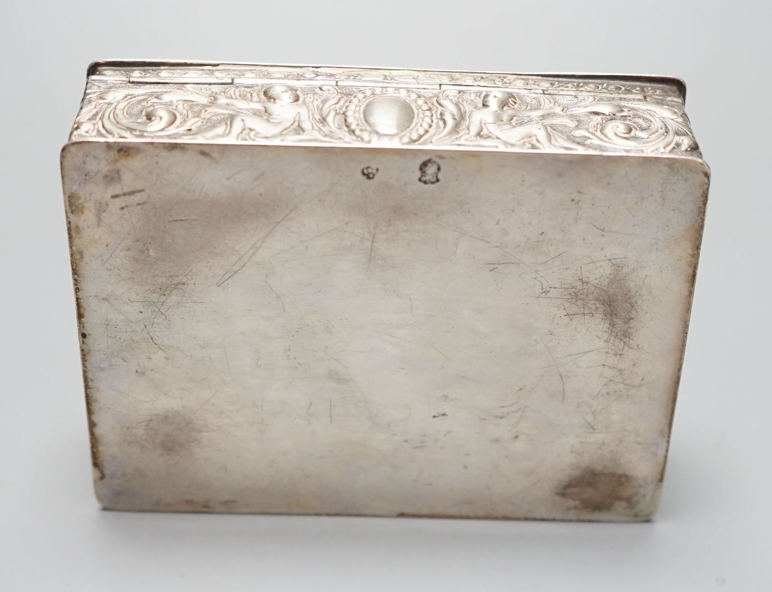 A late 19th / early 20th century German Hanau silver rectangular box and cover, the top embossed with a scene of revellers, import marks for London, 1912, 11.7cm.